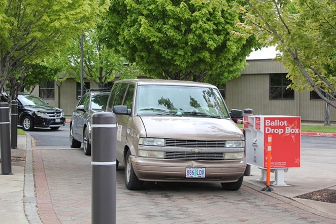A line of cars forms behind one of Bend's busiest ballot drop box sites at the Deschutes County Clerk’s office at 1300 NW Wall Street. - LAUREL BRAUNS