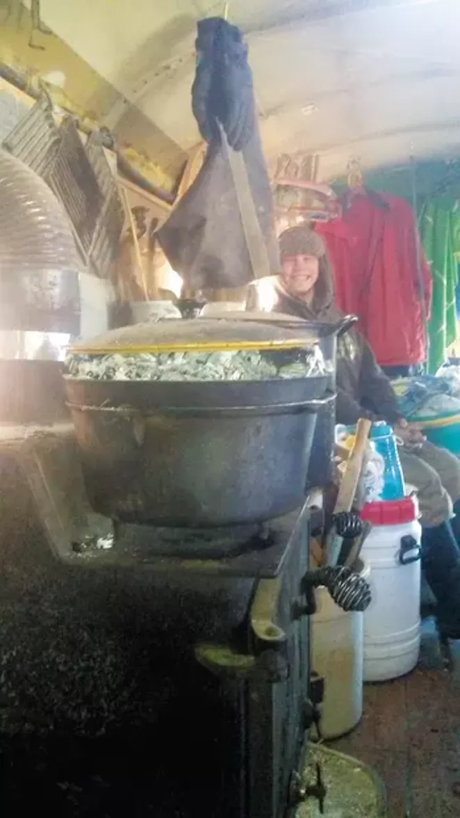 Cindy Looney's woodstove and cook setup with her son in the background. - CINDY LOONEY
