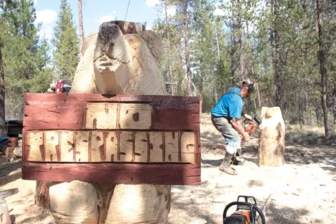 Woodchips fly all over Mosquito Bob's workspace as he carves a stump into a bear. He can turn a small log into a rough carving in about 30 minutes before painting, though larger statues can take months. - JACK HARVEL