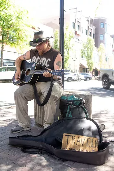 Traveling street performer "Wade," left, stops by to play on the corner of Bond and Minnesota. Wade, not being a local, was only passing through Bend. - KYLE SWITZER