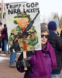 Dianne Esther shows the sign she painted as she and about 50 others protested outside Greg Walden's office on Feb. 27.