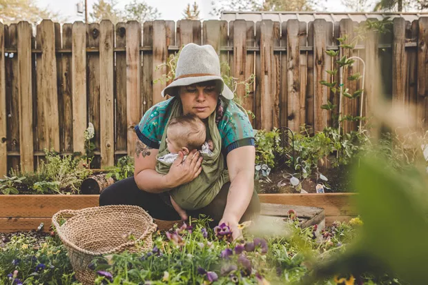 With her son, Forest, in a sling, Nickol Hayden-Cady harvests goodies from her garden. - TAMBI LANE PHOTOGRAPHY