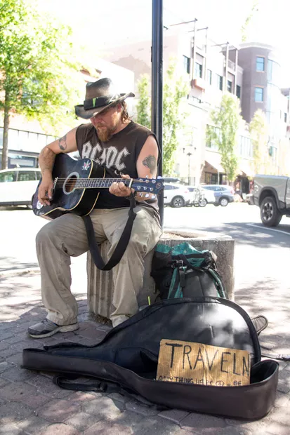 Traveling street performer "Wade," left, stops by to play on the corner of Bond and Minnesota. Wade, not being a local, was only passing through Bend. - KYLE SWITZER