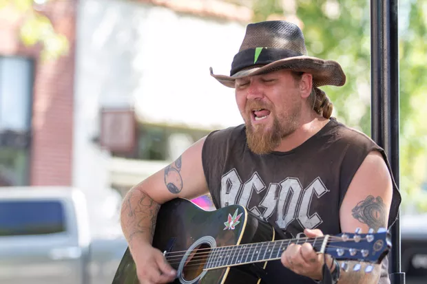 Traveling street performer "Wade," left, stops by to play on the corner of Bond and Minnesota. Wade, not being a local, was only passing through Bend. - KYLE SWITZER