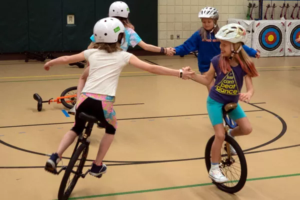 Four members of the Pine Ridge Elementary Unicycle Club practice riding in circles while holding hands. - CHRIS MILLER