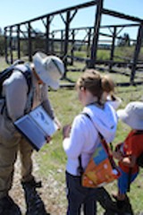 An adult in a sun hat showing a image of a bird to two kids. - Uploaded by DeschutesLandTrust1