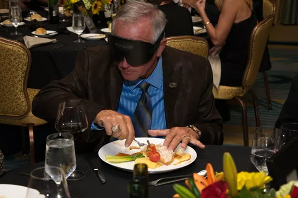 An attendee attempting to eat while blindfolded