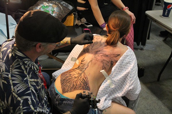 Don Osborne, Sparkle City Tattoos from Spartanburg, SC, works on Janet Smith's full back piece to cover up scars she was left with after a car accident. Osborne has been working for over five hours and still has a few more to go.