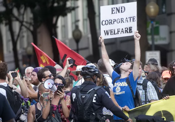 The police let a small group of protesters gather in the middle of the street at the entrance to the secure zone of the Time Warner Cable Arena. Here, despite being surrounded by police, they were able to get their message to passing participants of the convention.