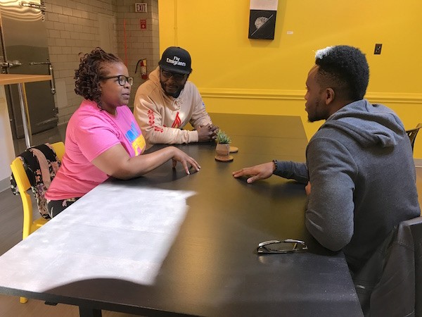 April Hood (from left), Eric Ndelo and Ifeanyi Ibeto plan their grand strategy inside the Hygge coworking space at Camp North End. (Photo by Mark Kemp)