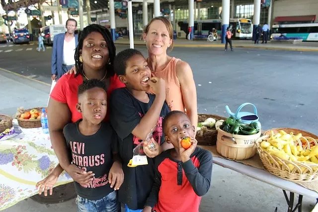 Caroline Miller (right) with Trenisha Birtha and her sons at the Transit Center market that they run for The Bulb on Thursdays. (Photo by Ryan Pitkin)