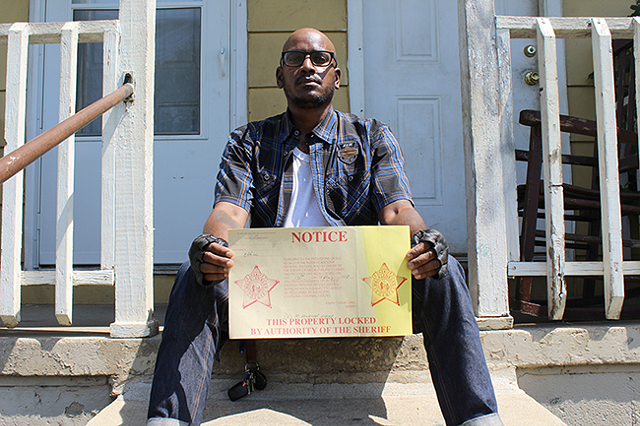 Jacobs holds an eviction notice placed in the door of a Brookhill Village home in May. (Photo by Ryan Pitkin)