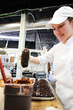 An Amelie's employee dips an eclair. (Photo by Meredith Jones)
