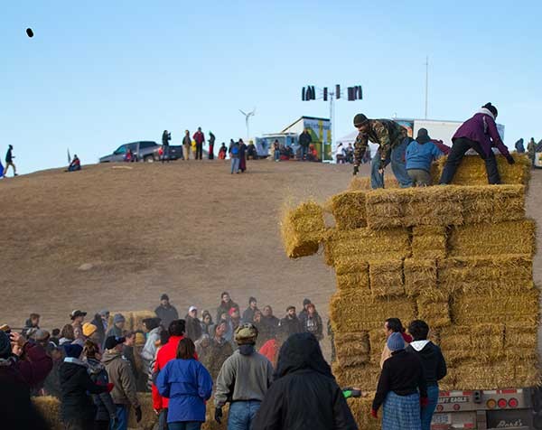 Water protectors in the Oceti Sakowin camp prepare hay that will be used for insulation during the coming winter. - GARRETT AMMESMAKI