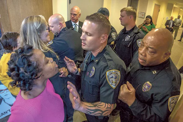 UNC Charlotte student Ashley Williams (pink shirt) and other protesters confront campus police during an attempt to enter the board meeting. (Photo by Grant Baldwin)