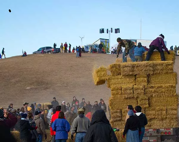 Water protectors in the Oceti Sakowin camp prepare hay that will be used for insulation during the coming winter. - GARRETT AMMESMAKI