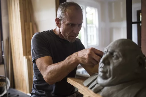 ArtPop alum Nicholas Sorlien works on one of his concrete heads. (Photo by Katie McLean)