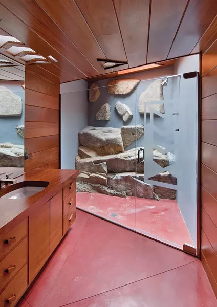 A guest bathroom with protruding boulders and skylight.