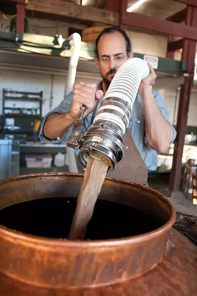 Christopher Williams dumping fermented mash in the still. - ROY GUMPEL