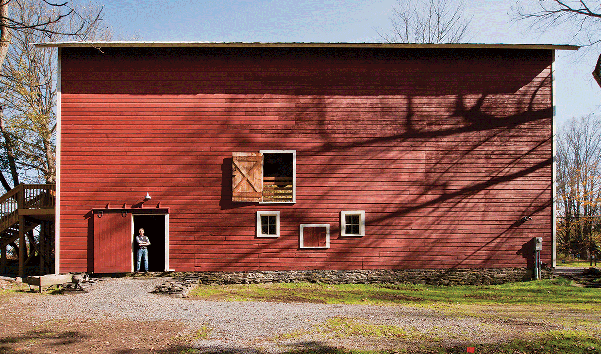 Giessinger standing in the rear door of the three-story barn, renovated to host events. - DEBORAH DEGRAFFENREID