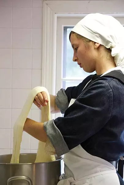 Gwyneth Owen, a former intern who is now a Postulate, stretches mozzarella curds. - PETER BARRETT