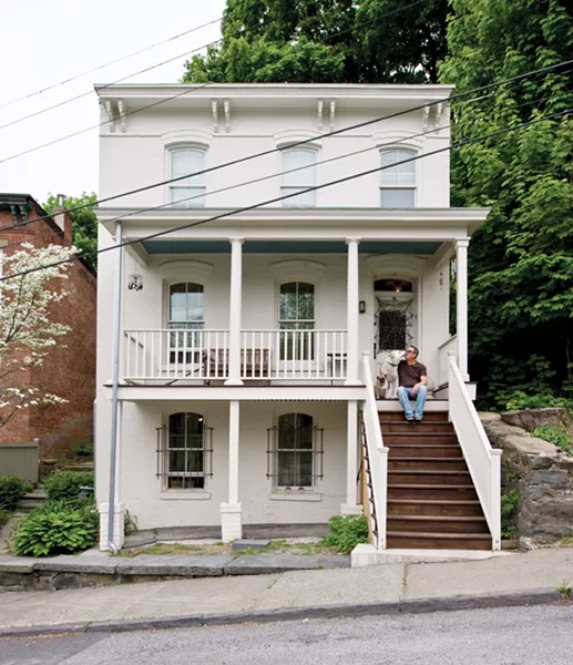 Jonathan Korn on the porch of his gutted and rebuilt home on Ravine Street in Kingston with his pug Jobim and shepherd Jazz. - DEBORAH DEGRAFFENREID