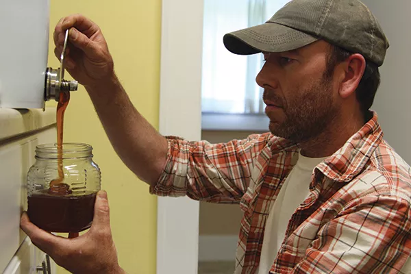 Jorik Phillips fills a jar with his honey. - PETER BARRETT