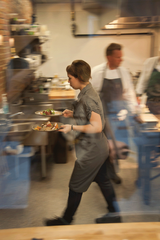 Morgan van Alstyne bringing food to table from the kitchen.Photo by Roy Gumpel.
