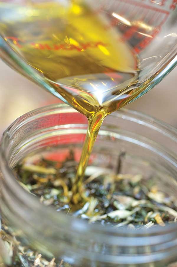 Pouring olive oil into an herb mixture.