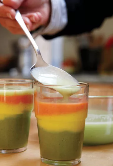 Spooning feta-yogurt emulsion onto the Greek salad parfait. - . PRESTON + SCHLEBUSCH