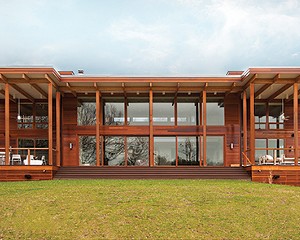 The dramatic large overhangs on the south wall facing the pond shield the home from unwanted summer solar gain, while the walls of glass provide passive solar heating in winter. Lindal’s signature Western Red Cedar siding complements the desi