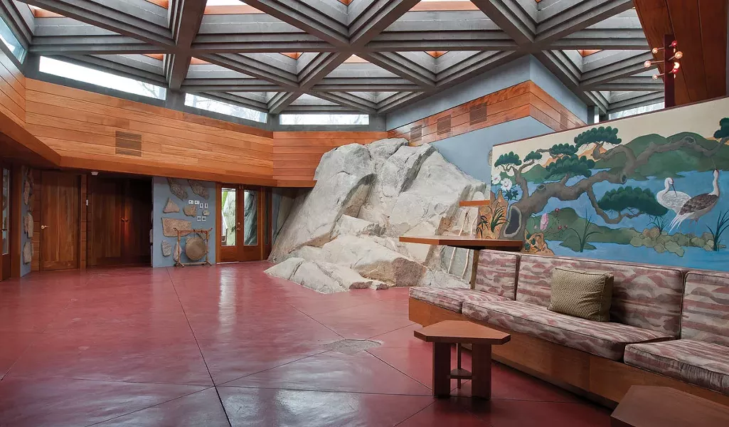 The entryway to the main house, with 26 triangular skylights set in a concrete grid and a massive boulder extending outward adjacent to the front door.