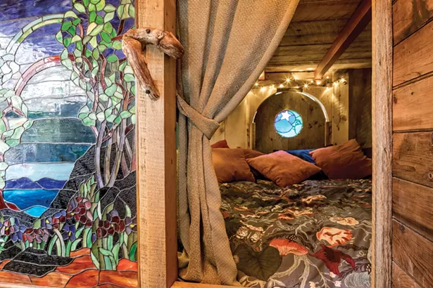 After cutting out the back half of the bus’s metal roof, Quick built a queen sized loft bed under a raised wooden roof. Below another full sized bed offers extra sleeping space. Quick took a stained glass from his previous residence and installed it at the bunk’s entrance. At the back he installed a circular stained glass window depicting the moon. - PHOTO BY WINONA BARTON-BALLENTINE