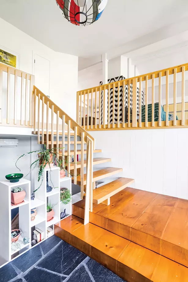 The couple completely remodeled the home’s front entryway by sanding the floating staircase and adding new railings. At the lowest level, they replaced the railing with a built-in bookcase for both succulents and books. - PHOTO BY WINONA BARTON-BALLENTINE
