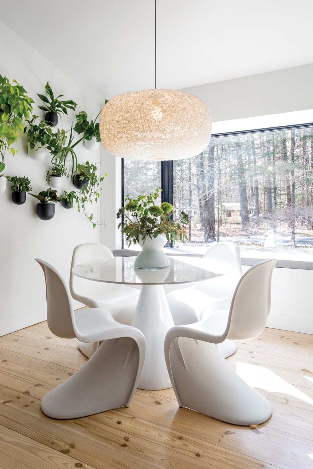Sun floods into Oldenburger and Smykowski’s kitchen, - even on winter days. The thriving wall garden adds layers of - green to the beige-on-white design. Oldenburger found two - of the Vernor Panton chairs by Vitra at a vintage shop and - matched them with a round table and pillar pedestal base. - The wall pots and hanging lamp are both by West Elm. “I do - love plants,” she says. “I try to have live plants throughout - the house and encourage my clients to also.” - PHOTO BY WINONA BARTON BALLENTINE