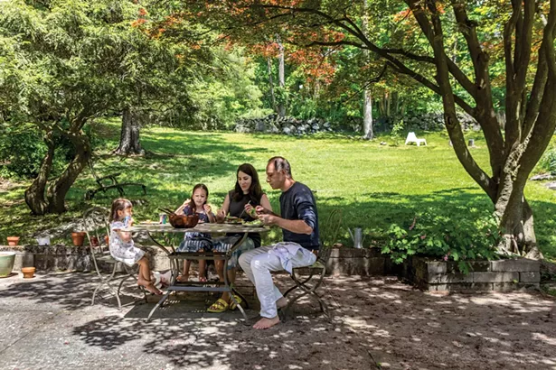 Winick, Bloomberg, and their daughters enjoying a meal on their backyard patio. “We also have a covered porch,” says Winick. “It’s our own outdoor living room and dining room and we use it as many days as the weather allows.” - WINONA BARTON-BALLENTINE