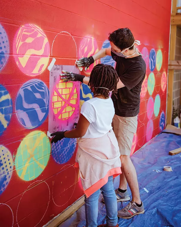 A local student works with a Reher Center staff member on the "Stitched Together" exhibit, which collected and amplified the voices of female garment workers.
