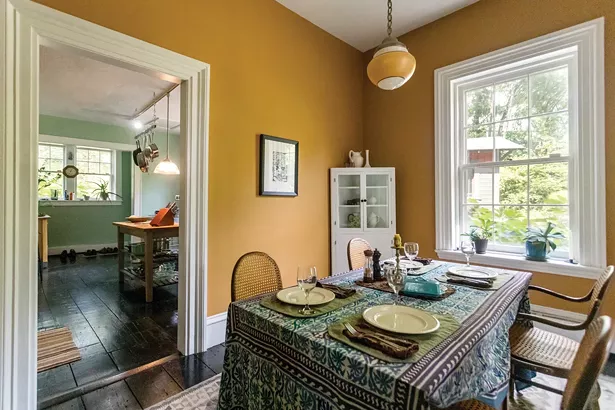Hanging above the dining room table is a print by Swiss-American Surrealist painter Kurt Seligmann, an expert on magic and the occult. “His book The Mirror of Magic is a much-used reference in my library,” says Bransford. Through the doorway, the home’s kitchen was moved from the basement to the first floor as a later addition to the house.