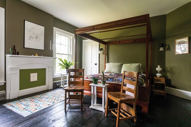 A second-floor bedroom features a handmade Thai wood canopy bed and two antique 1940s school chairs. “I find myself unconsciously pairing old and new things,” says Bransford of his decorating style. “I’ve also come to love plants, especially ferns. They have a lot of say about what goes where in terms of furniture placement.”