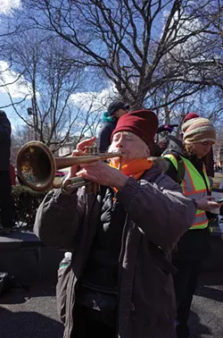 Amy Trompetter sounds a musical protest at the People's March for Education Justice. - FIONN REILLY