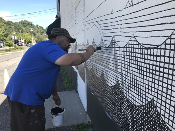 Matthew Pleva works on a mural at the Riverport Wooden Boat School for O+ Kingston. - KATHLEEN MURRAY