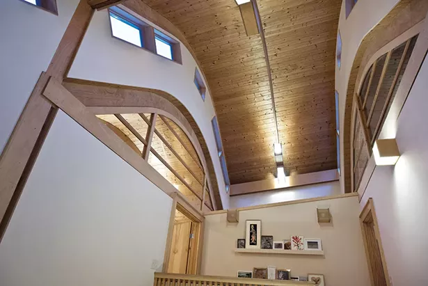 The home’s barrel-vaulted ceiling and multiple interior and exterior windows enhance the bright, boundless space. A mix of the couple’s own artwork, friends’ pieces, and family photos line the walls. - DEBORAH DEGRAFFENREID