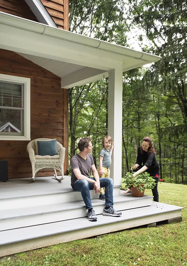 Bollman and Nicholas with their son Hudson on the front veranda. The home’s construction “was a collaboration—my wife and I drove the whole process,” says Bollman. However, their new neighbors stepped in and helped with everything from the tear down to the milling to the framing and construction. - DEBORAH DEGRAFFENREID