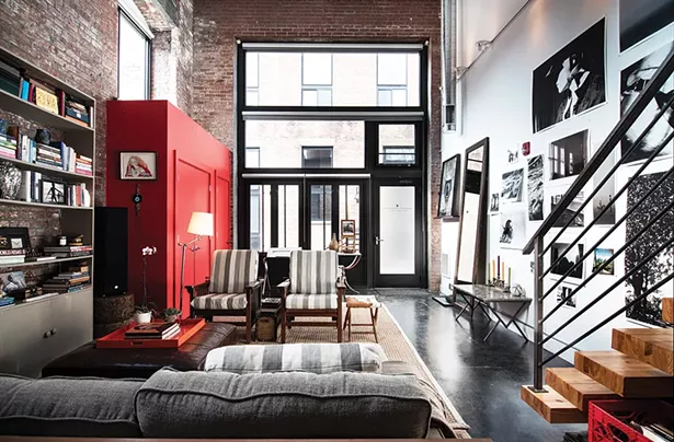 The front end of the loft is dominated by a bright red closet Rice added when she moved in. The striped grey chairs were upholstered with fabric from Sylvester & Co. in Sag Harbor, NY and paired with a cowhide bench made by Amy Pilkington. The marble coffee table in the foyer is from Maison Gerard in New York. - PHOTO: DEBORAH DEGRAFFENREID
