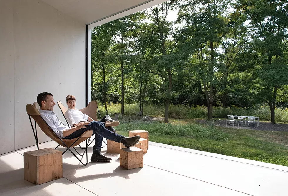Stella Betts and David Leven look out at their property’s surrounding campsite. The covered porch, which features retractable screen walls, “is actually one of our favorite rooms in the house,” Betts says. “Our designs are committed to capturing the relationship - between the amazing, the sublime, and domestic space through the interplay of elements and crossing boundaries between inside and outside,” Leven adds. - PHOTO: DEBORAH DEGRAFFENREID