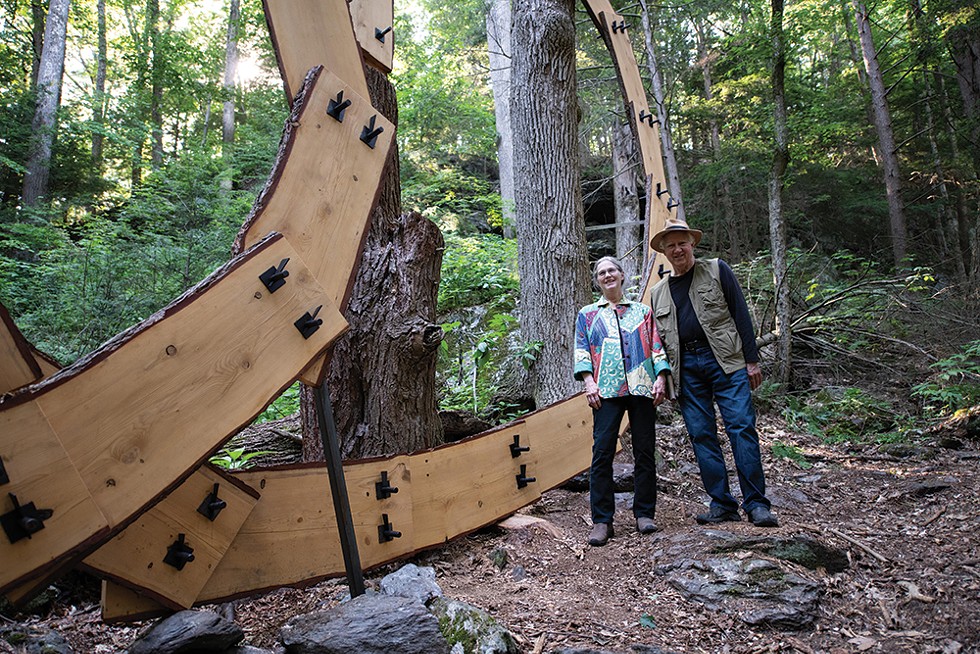 Artists Laura and Rick Brown stand before - Dreaming, which was created by connecting lumber from a storm-downed hemlock to a living ash tree. - PHOTO: KARI GIORDANO