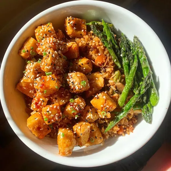 Vegan crispy tofu special with vegetable fried rice and chili sauce.