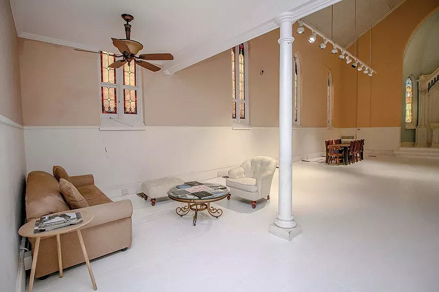 A seating area under the choir loft turned bedroom enjoys afternoon light through the stained glass windows. “The quality of light in this region is incredibly special. One of the reasons so many artists have migrated to Hudson over the past 200 years is for the light,” Bokaer says. “On winter afternoons around four that light phases through these windows—it’s breathtaking.” - PHOTO BY SETH DAVIS