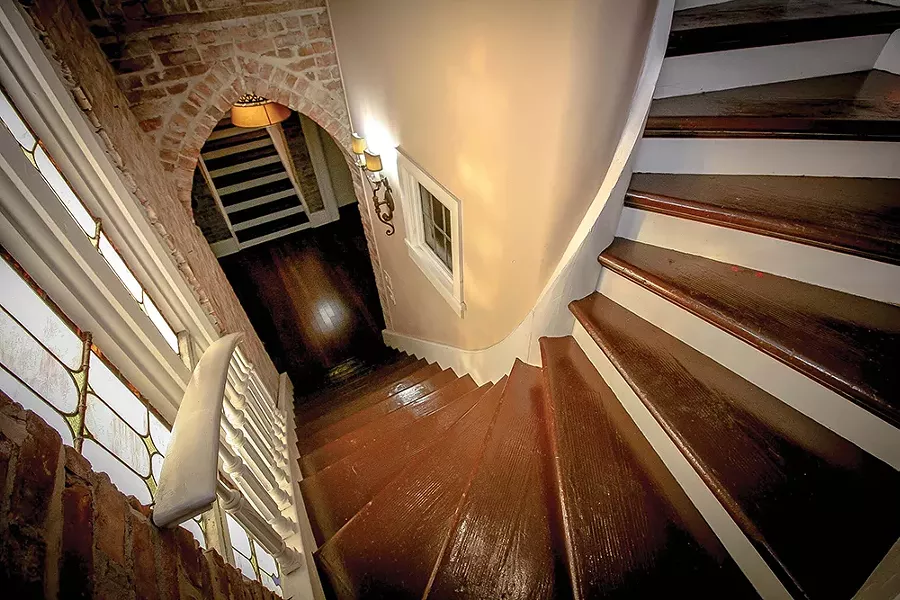 A winding staircase leads from the entryway to the lofted bedroom. Bokaer has kept the minimalist aesthetic throughout the home, letting the stained glass, exposed brick, wood trim, and architectural flourishes take the spotlight. - PHOTO BY SETH DAVIS