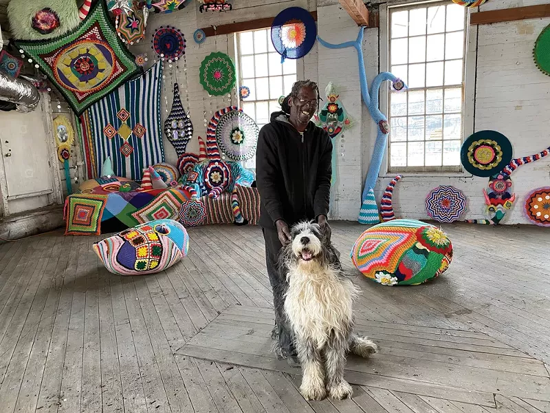 Gallery visitor Josh Shaw with ArtPort dog-in-residence Rubi(n) in front of an installation by Jelia Gueramian inside the Cornell Steamboat Building in Kingston - PHOTO BY STEFAN SAFFER